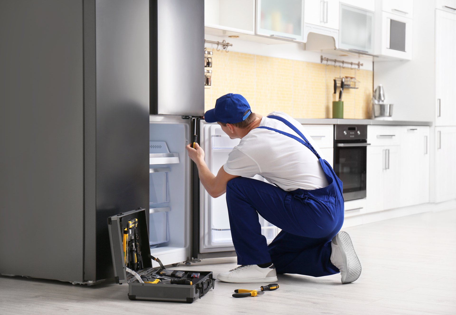 a technician repairing a refrigerator - Scranton Appliance Repair Pros