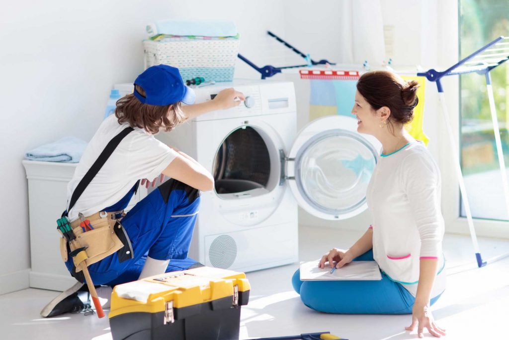 a technician repairing a washer while woman is watching - appliance repair service scranton