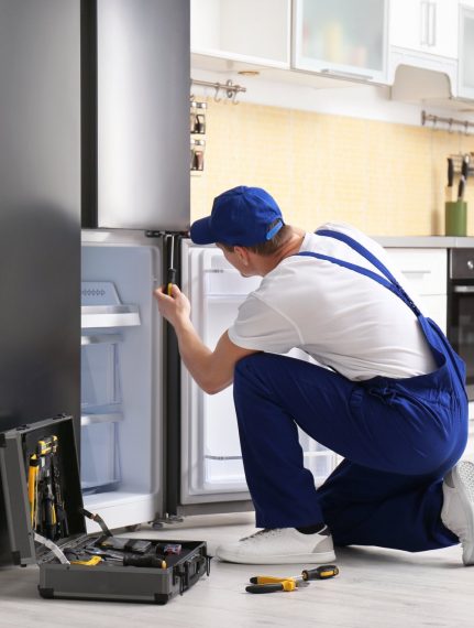 a technician repairing a refrigerator - Scranton Appliance Repair Pros